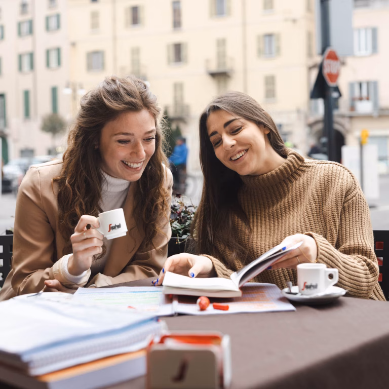 Imagebild: Gesprächssituation mit 2 jungen Frauen an einem Tisch mit Kaffeetassen und Büchern
