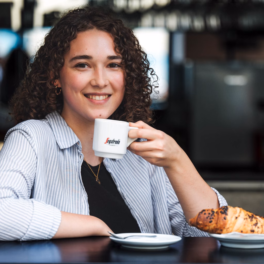 Imagebild junge Frau mit einer Tasse in der Hand und einem Croissant daneben